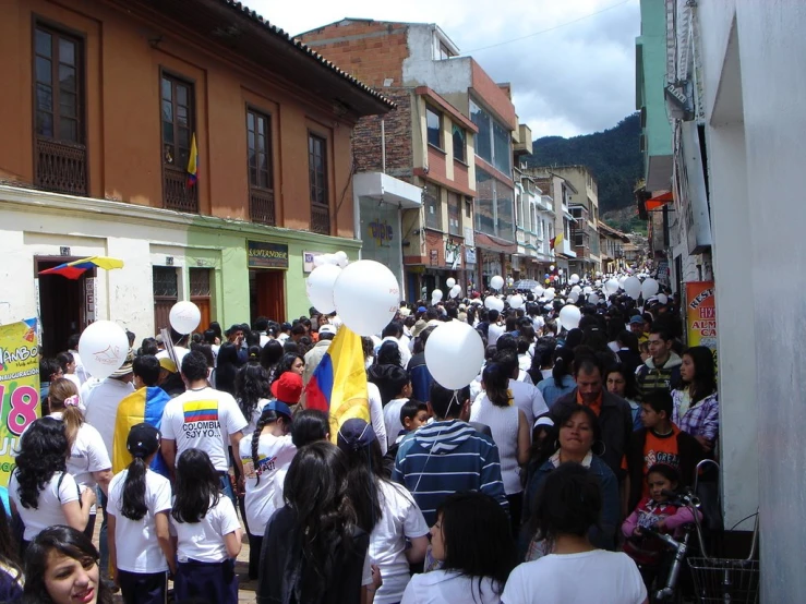 many people in white shirts walk down the street