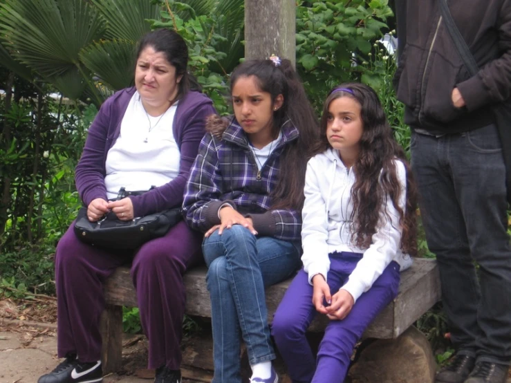 three girls in purple pants are on a wooden bench