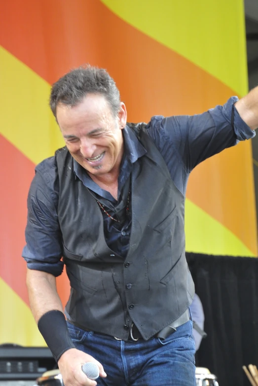 a man with his arm extended and his eyes closed, in front of a multi colored stage backdrop