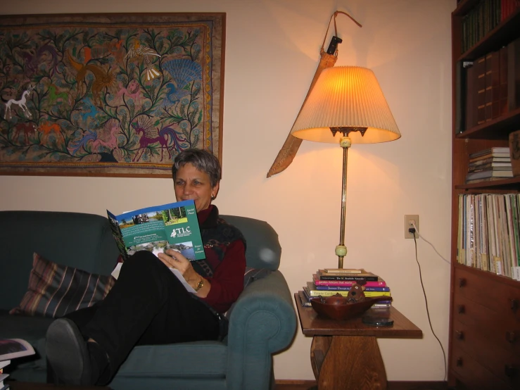 a woman that is sitting on a couch holding up some books