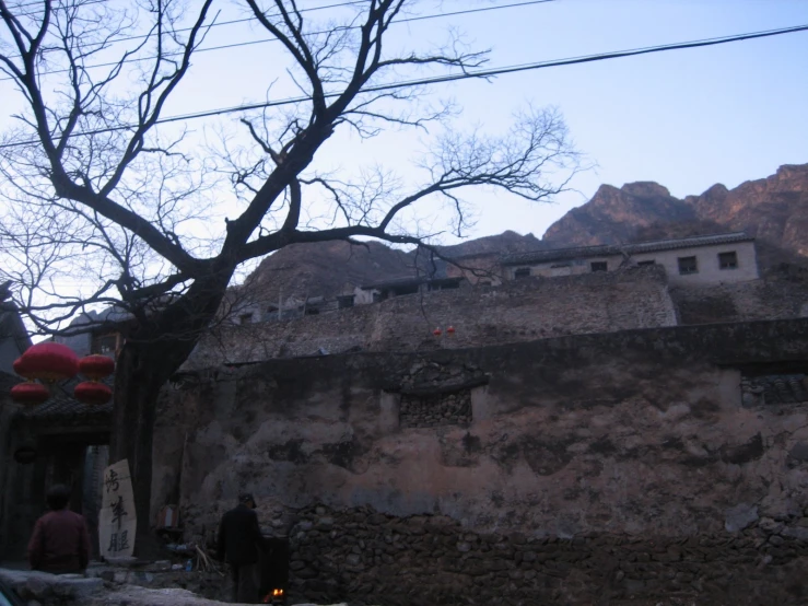 a stone wall is near a tree and another building