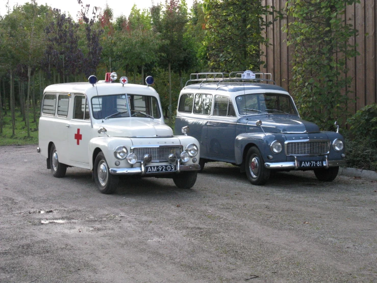 two old vehicles are parked in the gravel