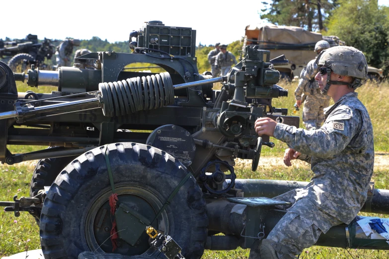 a soldier in camouflage working on an army gun