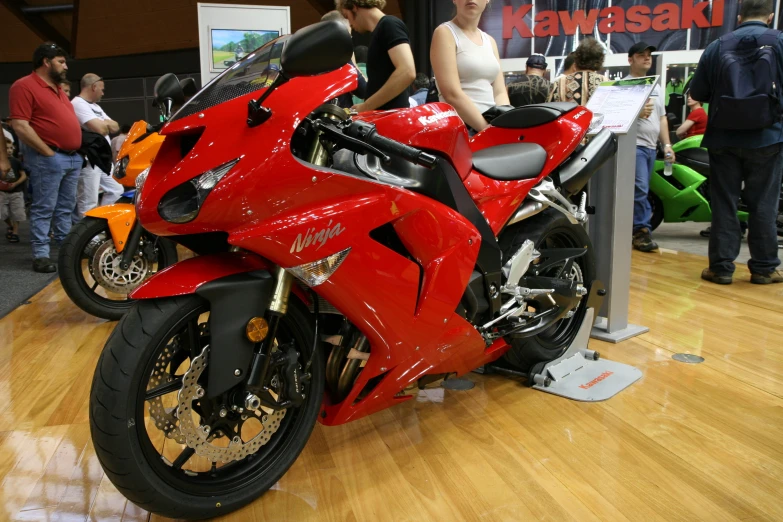 a red motorcycle on display on a wooden floor