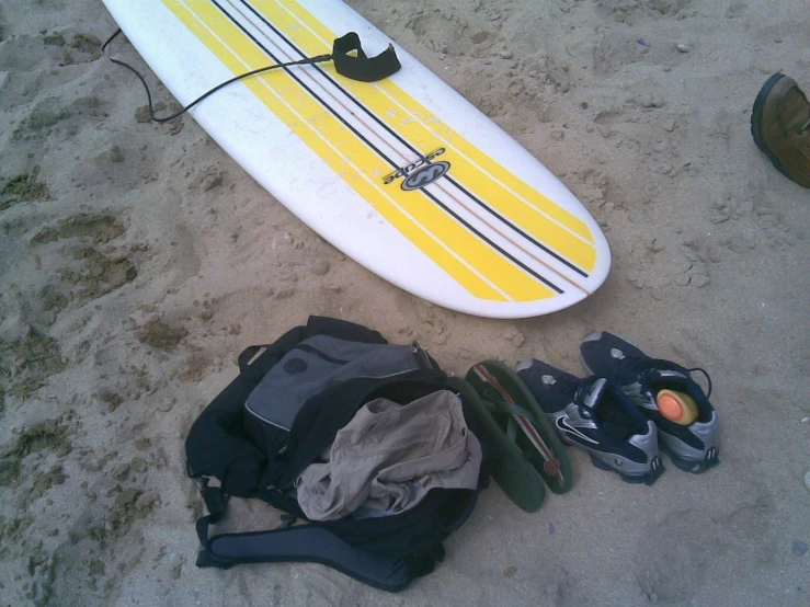 a white and yellow surfboard sitting on top of sand