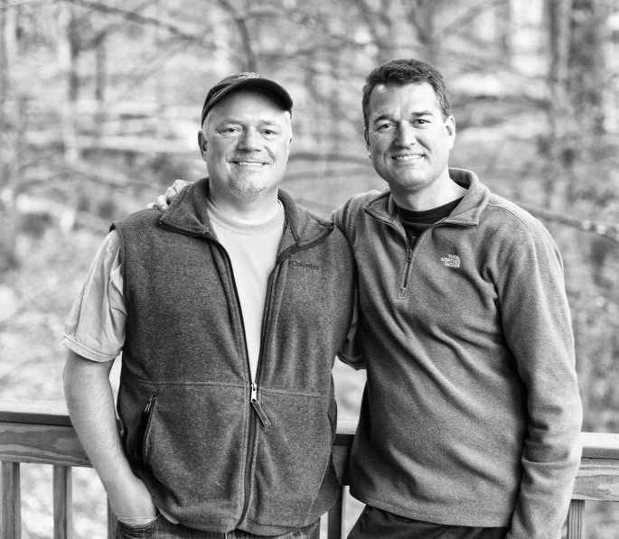 two men stand next to each other on a railing