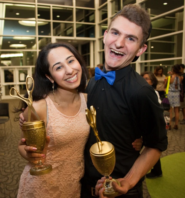 a man and woman smile holding trophies