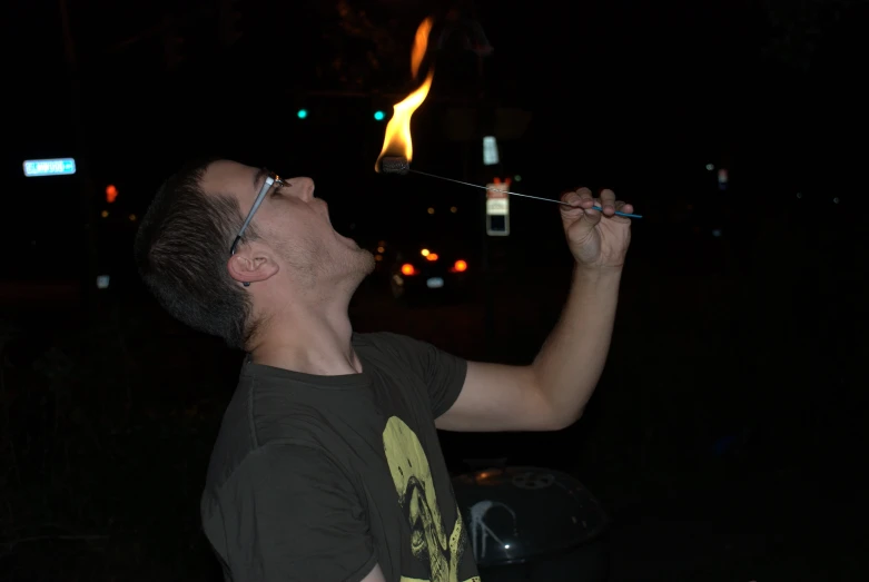 a person wearing a black shirt holds a lit cigarette in the dark