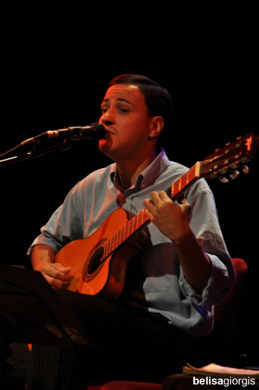 a man playing an acoustic instrument while sitting at a podium