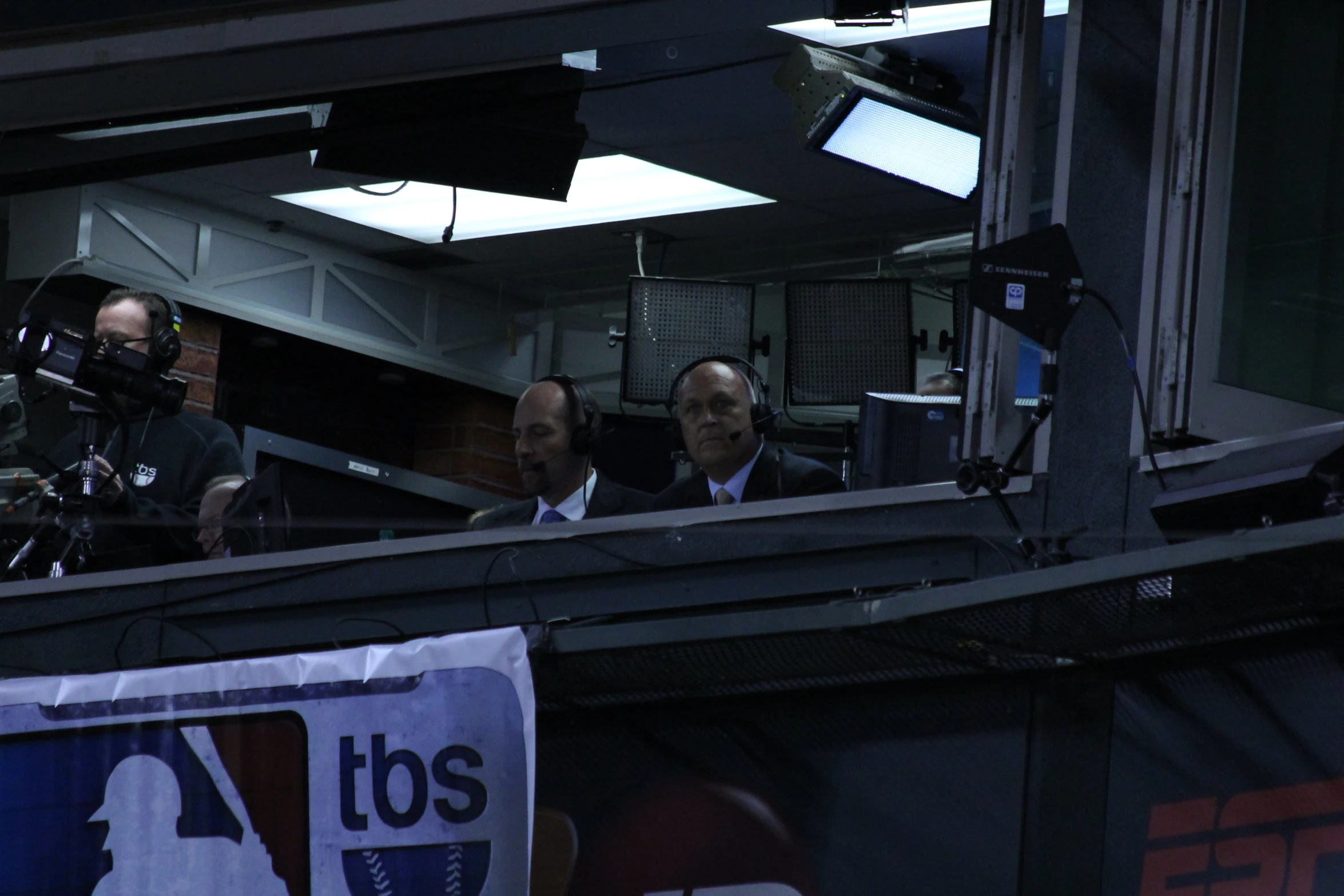 three men sitting in the stands holding cameras