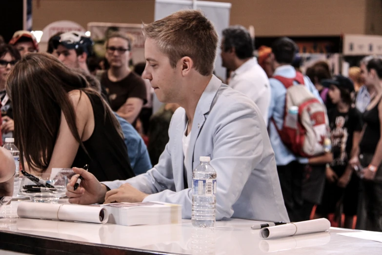 people sitting in an audience with water, water bottles and papers