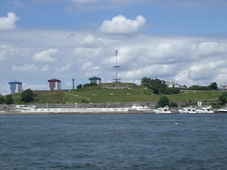 a large field on top of a green hill next to a body of water