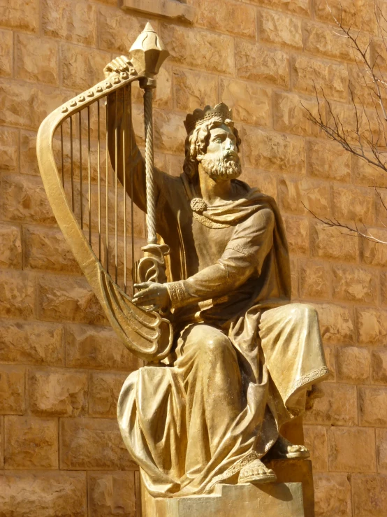 a golden statue of a man holding a harp