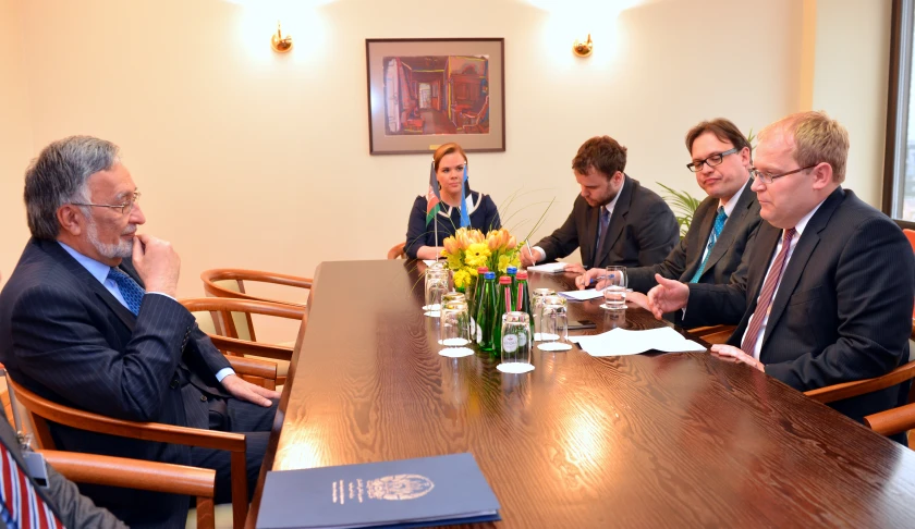 several business people are sitting at a table, with two men on cell phones