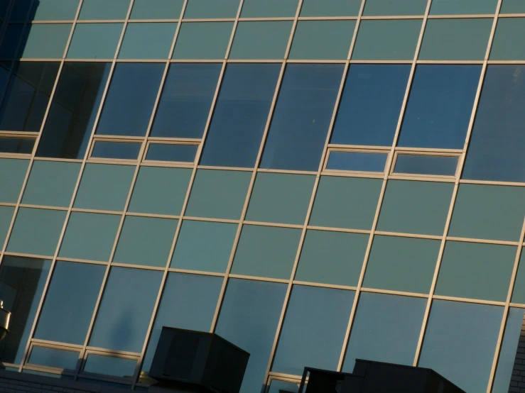 the side of a building has windows, and the reflection of a blue sky