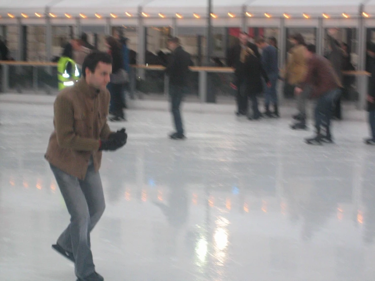 people skating on an outdoor ice rink with some walking on the ground