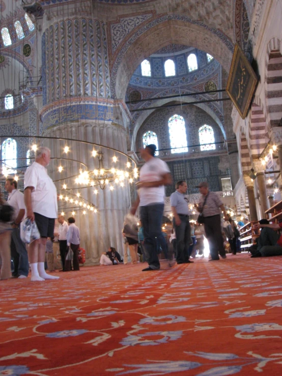 the carpet inside the building has many people standing around