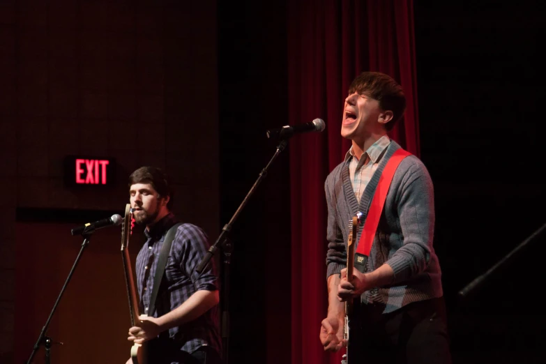 two male musicians are performing on stage