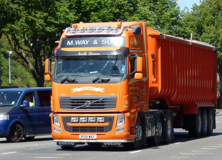 a orange semi truck traveling down a city street