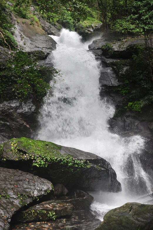 the waterfall is flowing into the water from a large rock