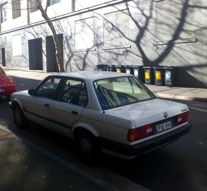 a white car driving down a street past another car