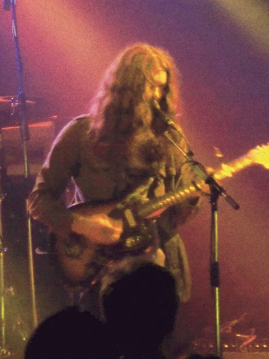 a man on stage playing a guitar in front of microphones