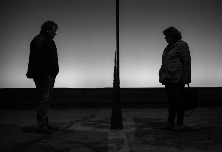 two men stand side by side next to a street light