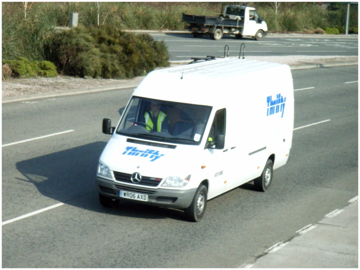 a small white van driving down a street