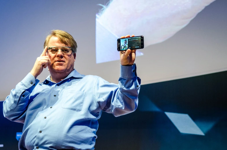 man with cell phone standing near projection screen