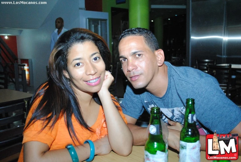 a man and woman pose with their beers at a restaurant