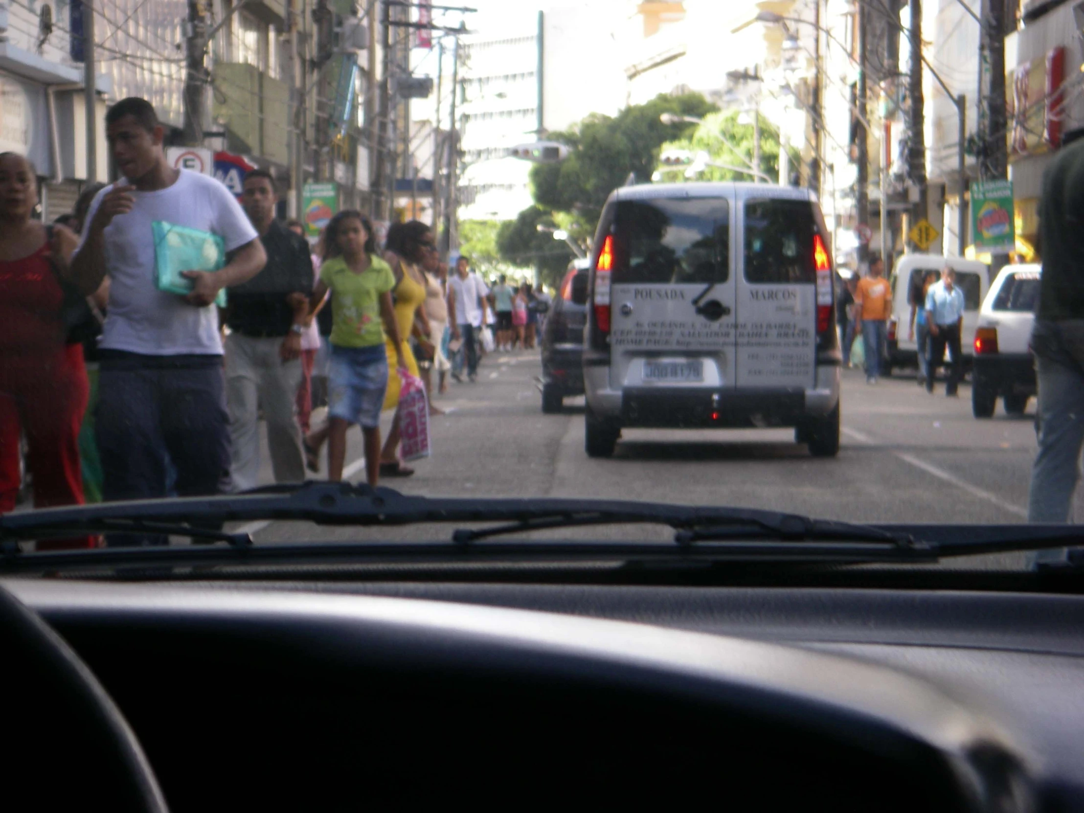 a group of people walk by vehicles on a city street