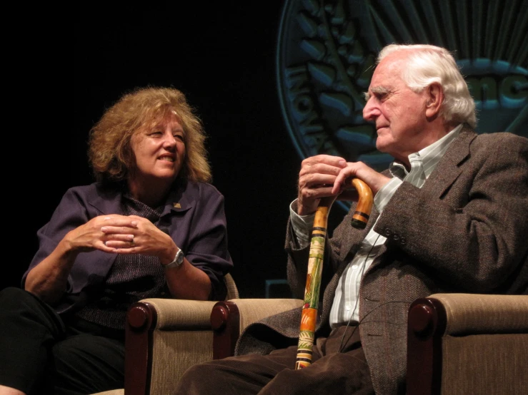 two people sitting on top of chairs together