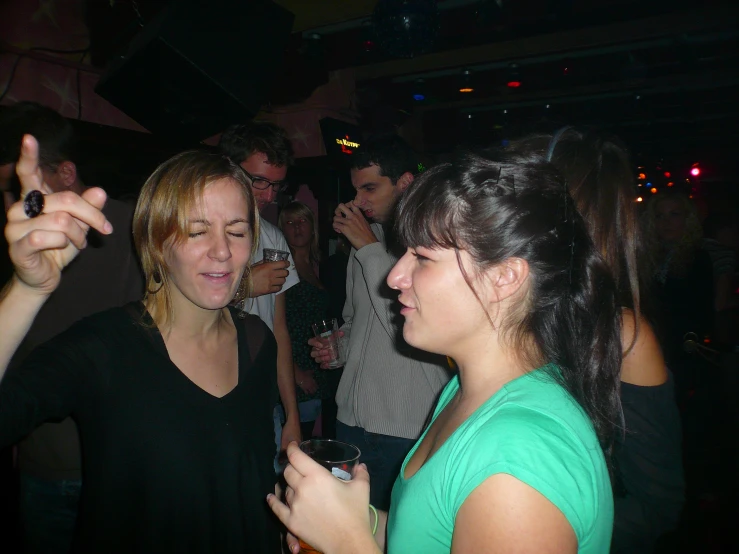 a woman talking to a woman in green holding a drink