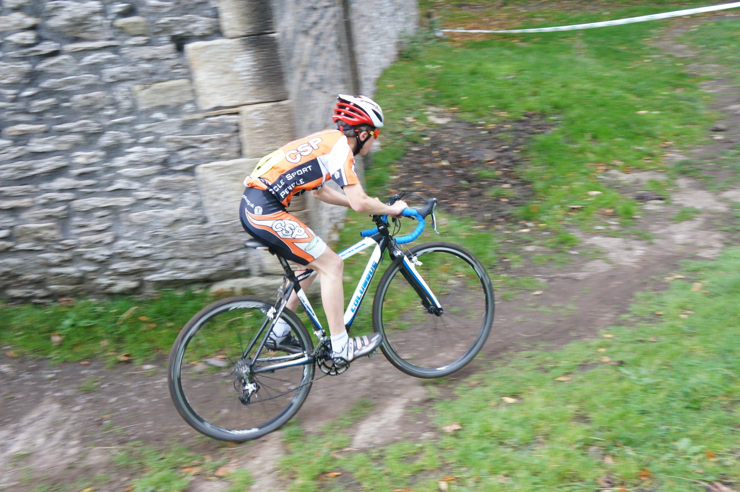 a bicyclist rides past a stone structure