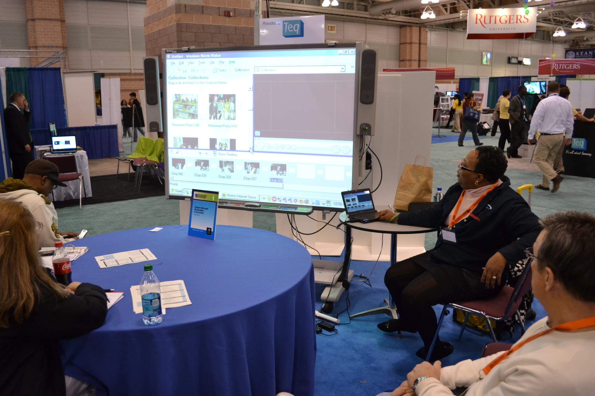 several people are sitting around talking in front of a projector screen