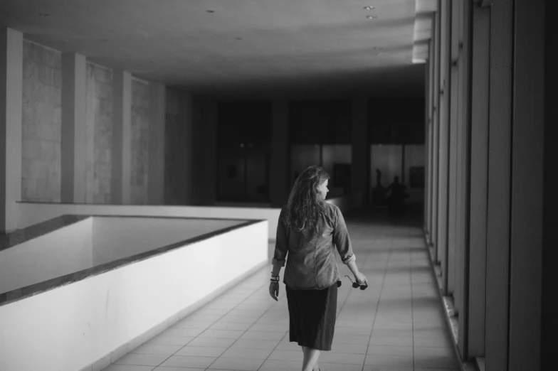 a woman walking down a long hallway next to tall buildings