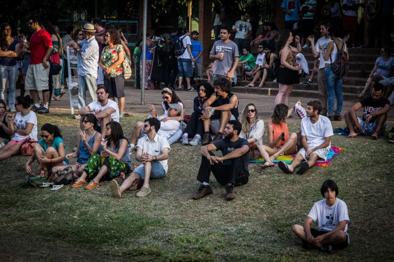 crowd of people sitting on the grass while others watch