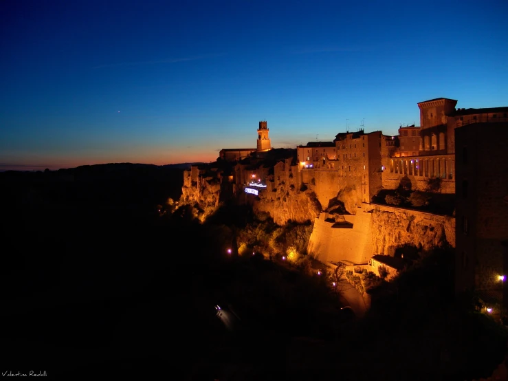 view of a city wall in the night, from an area just beyond a road