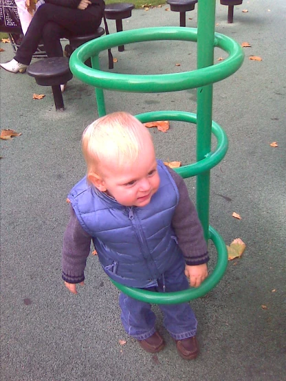 a baby plays on a small slide in the playground