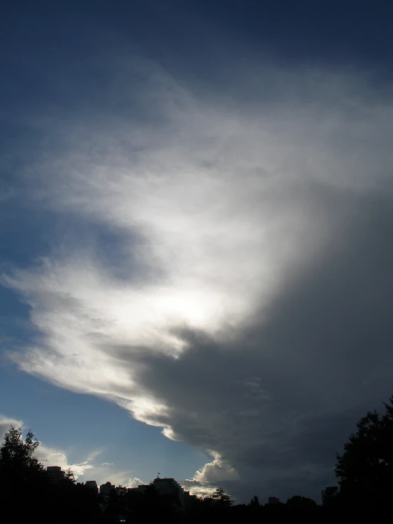 clouds in a sky near some trees at night