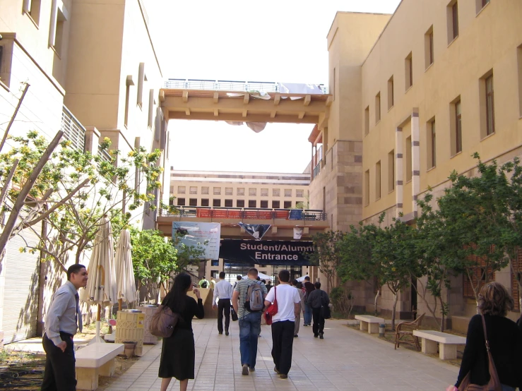 several people walking in an alley way with buildings in the background