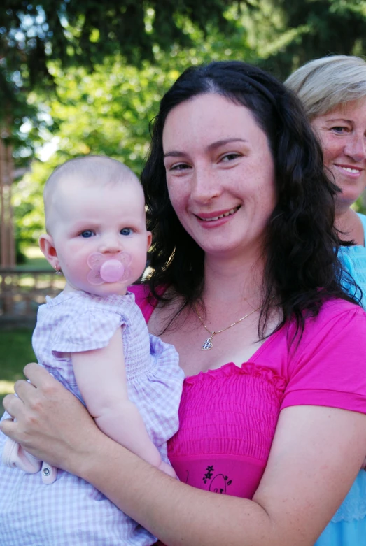 a woman holding a baby with the pacifier attached to it's mouth