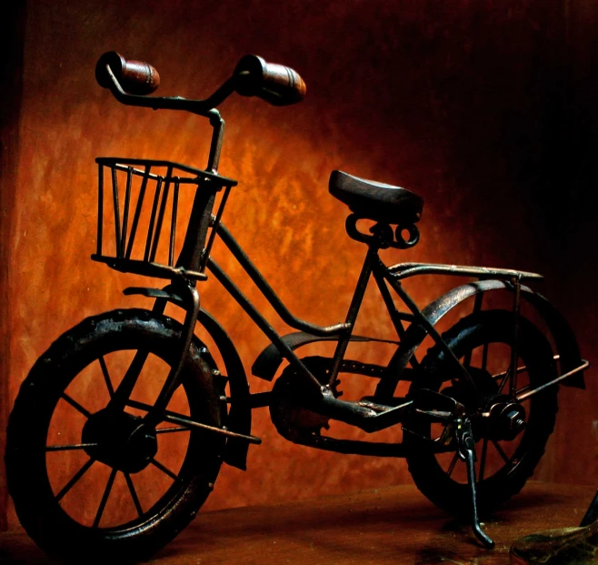 a metal bicycle with four spokes in front of a rusted wall