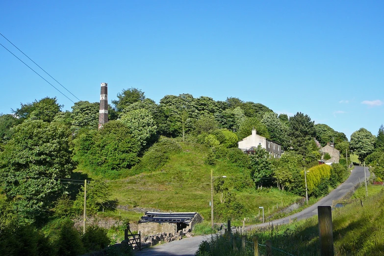 a hill with a road next to it near a forest