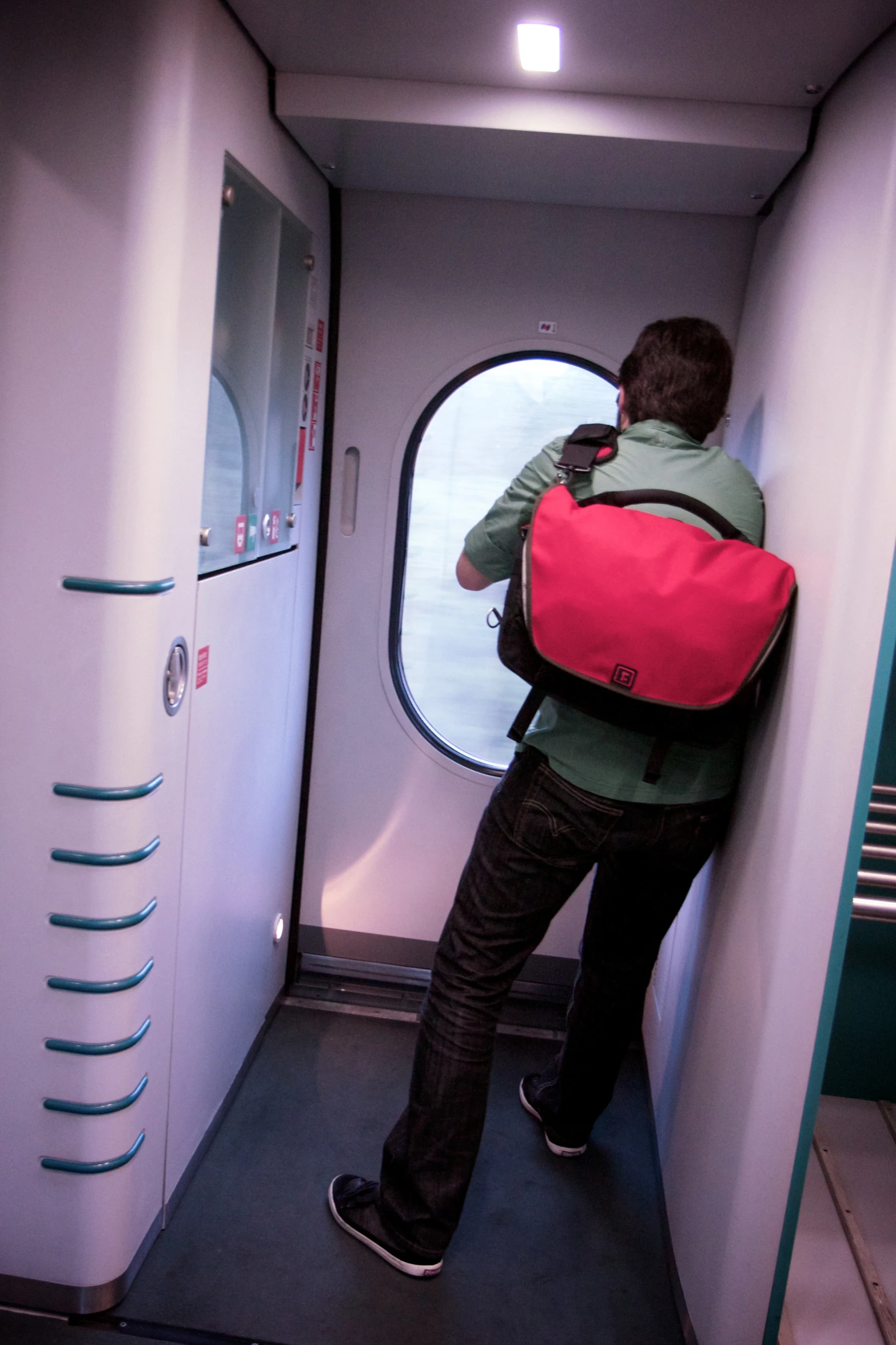 a young man with a pink backpack standing near a door