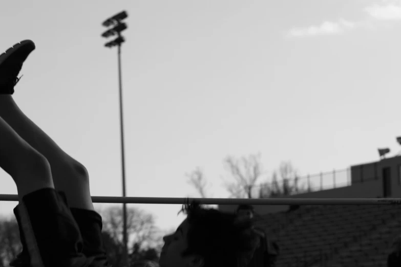 a woman on top of a metal bar with her legs in the air