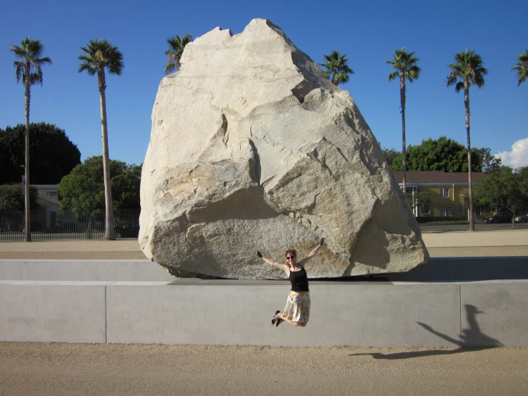 a woman is walking past a huge boulder