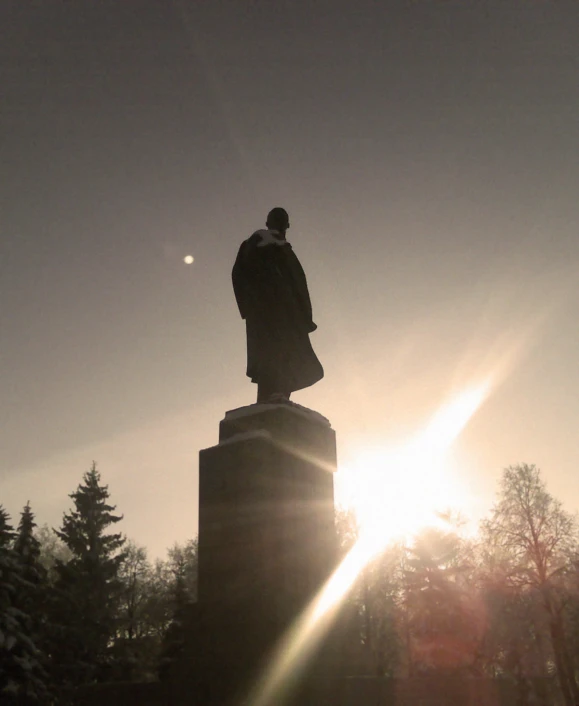 a statue in the winter with sun rays behind it