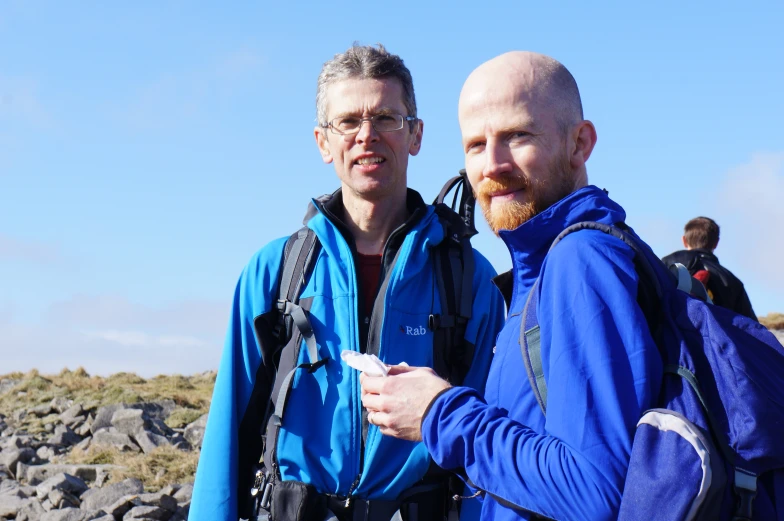 two men standing on a hill holding hands