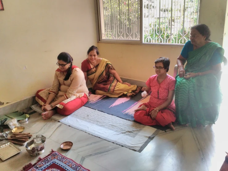 five people sit on the floor near some items